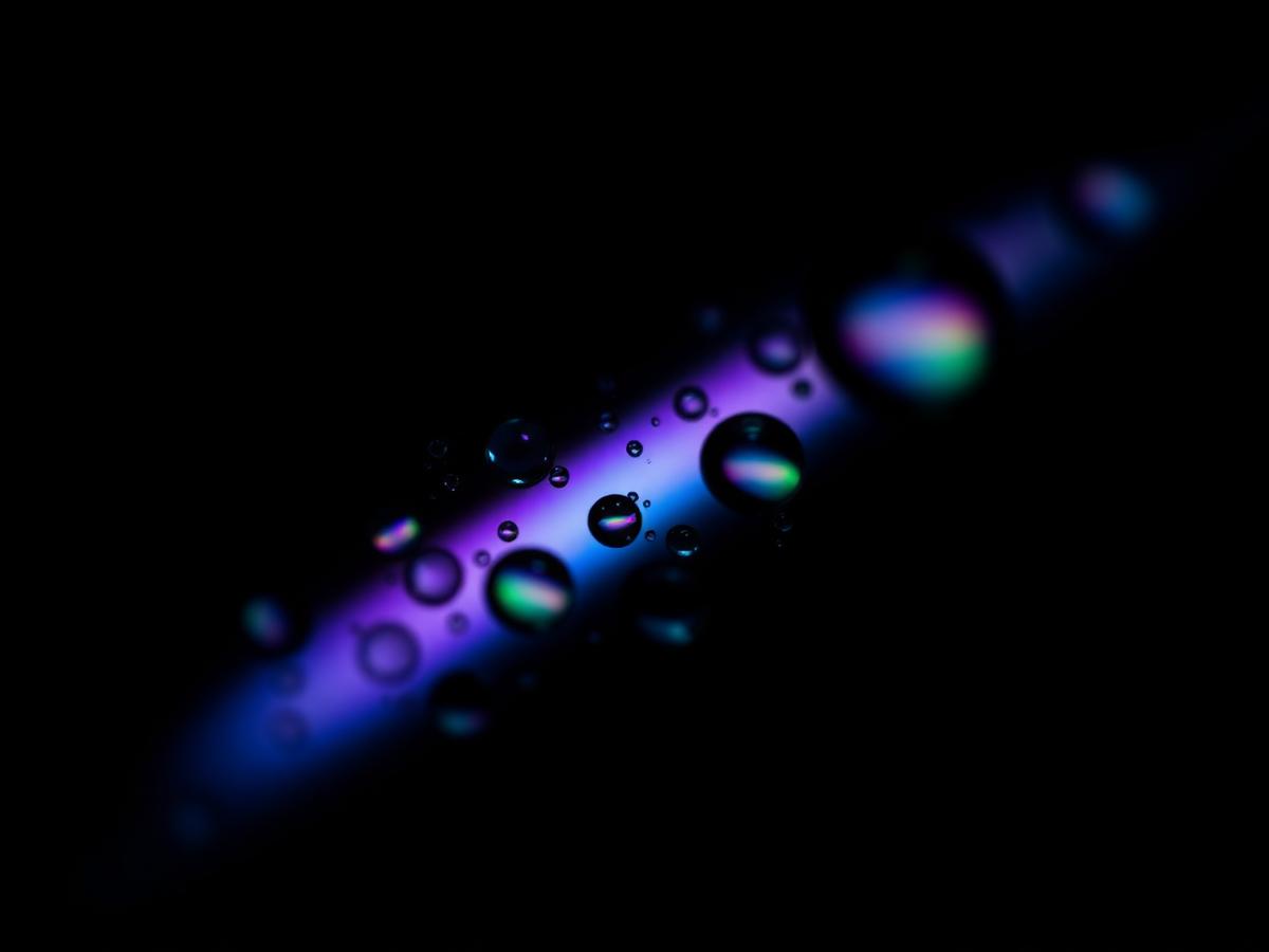 Macro de gotas de cristal refractando color iridiscente sobre negro
